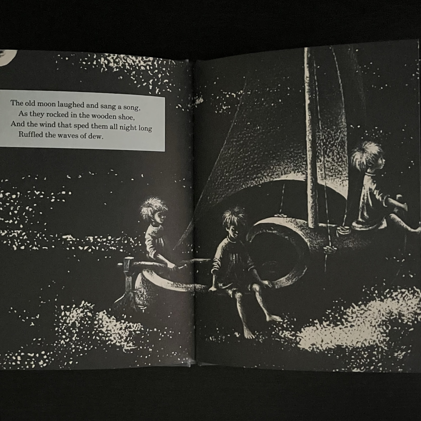 本のページの写真。男の子たちが木靴の舟の先端と縁に腰かけて星の海を進んでいます