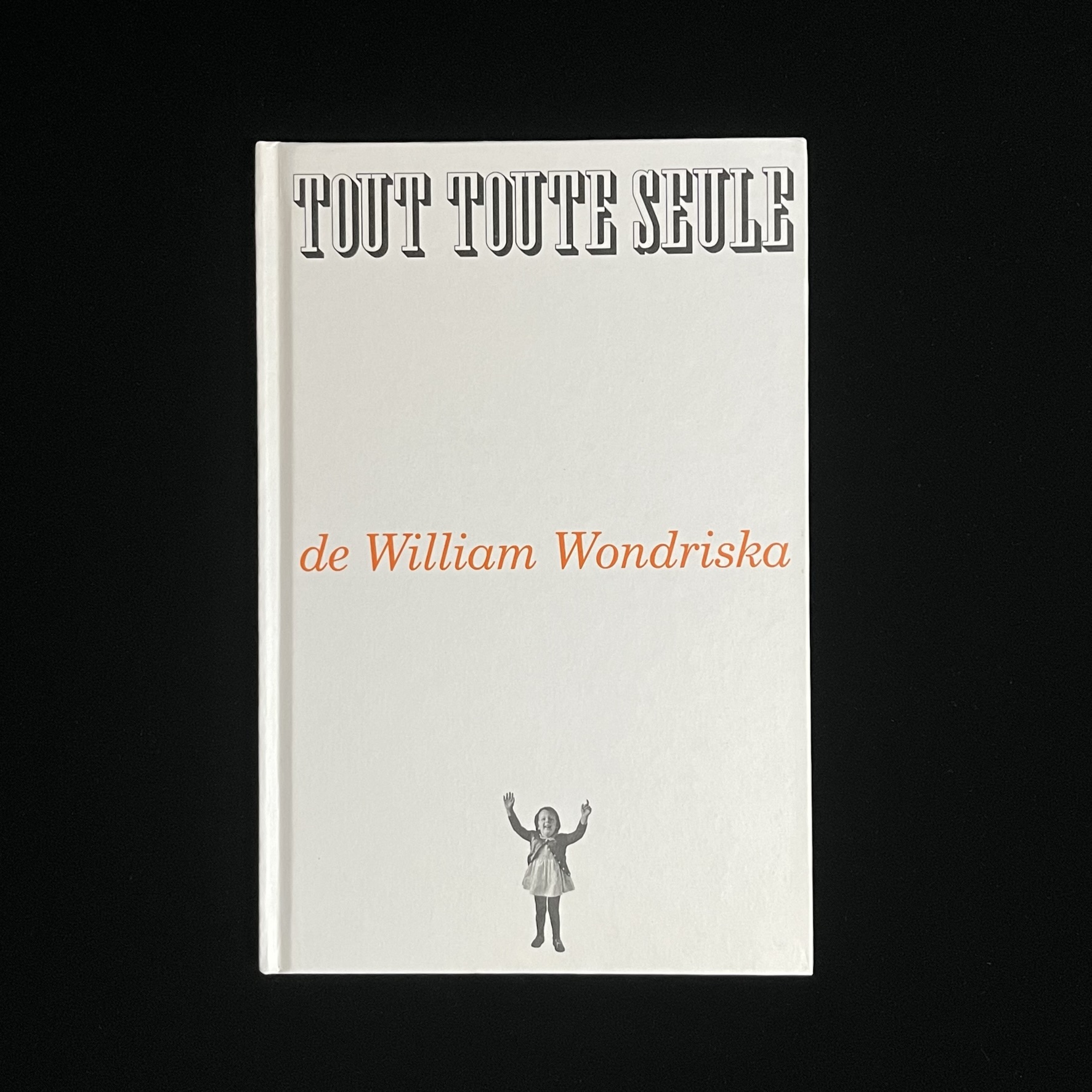 ウィリアム・ワンドリスカさんの「TOUT TOUTE SEULE」の絵本の表紙の写真。白い表紙にタイトルと著者名と女の子の写真のシンプルな構成でお洒落。女の子は笑顔で両手をあげている。