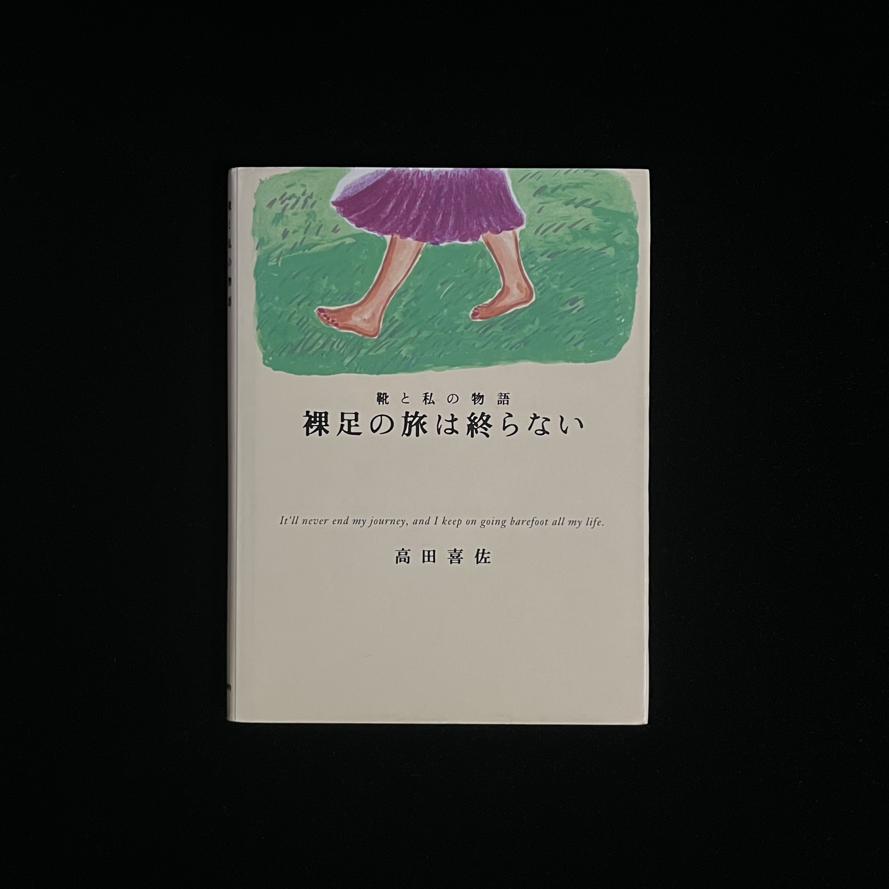 高田喜佐さんの『裸足の旅は終わらない』の表紙の写真。タイトルの上に、紫色のスカート姿の女性が緑の草の上を裸足で歩いている高田喜佐さんのイラストが描かれている。