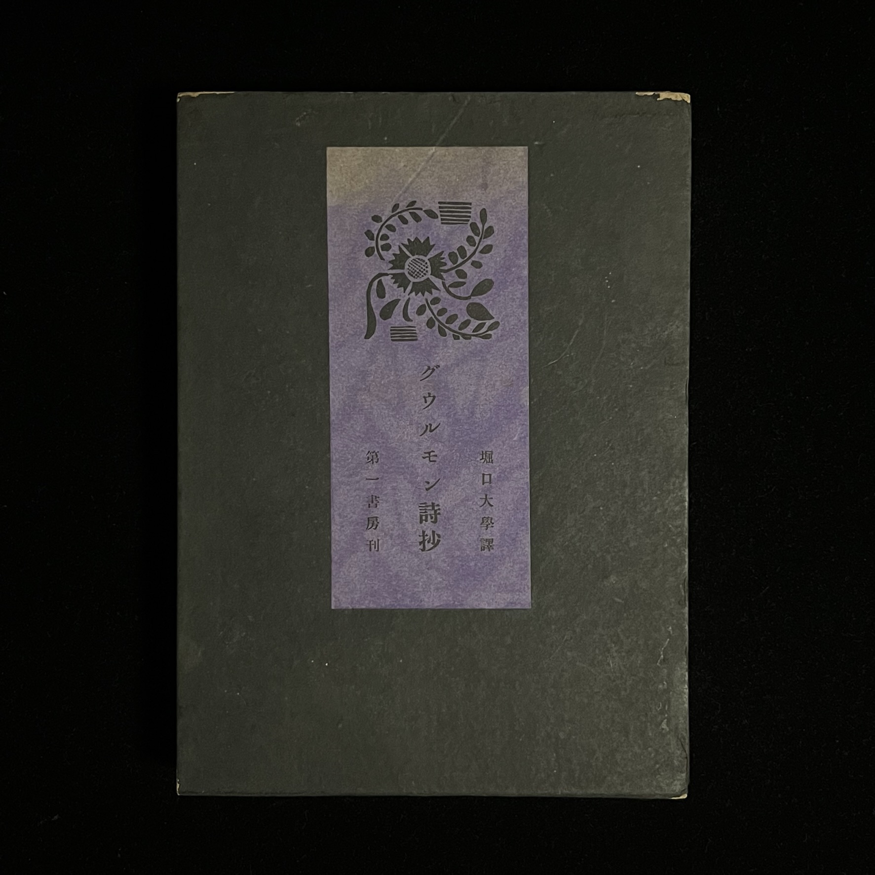 『グウルモン詩抄』の本の箱の写真。深い緑の箱の表紙の真ん中に文様の地と草花のイラストが描かれた紫色の紙が貼られており、タイトルと訳者の名前、出版社名が書かれています。