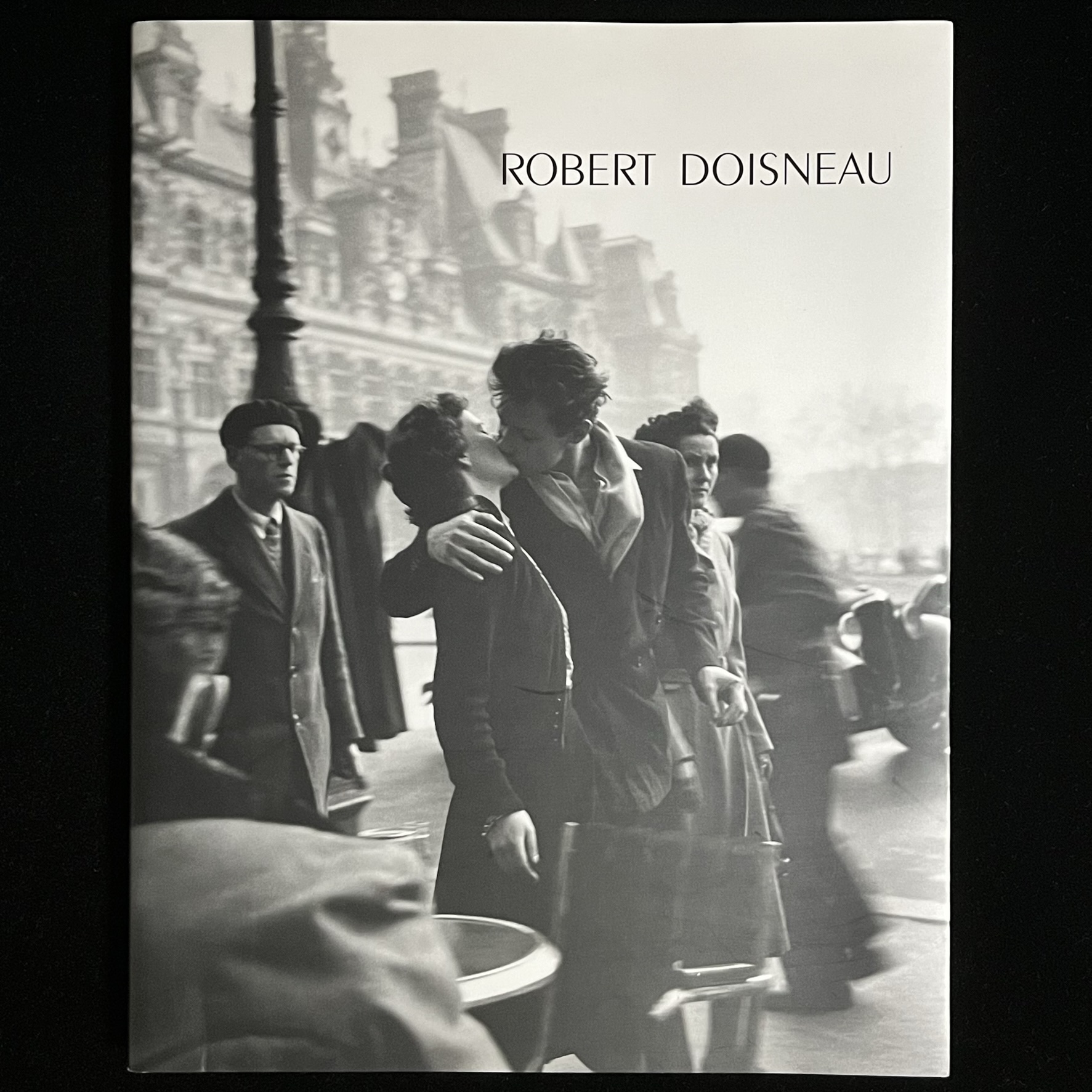 『ROBERT DOISNEAU』の写真集の表紙の写真。パリの街角の雑踏の中で、男女がキスをかわしている写真が載っています。