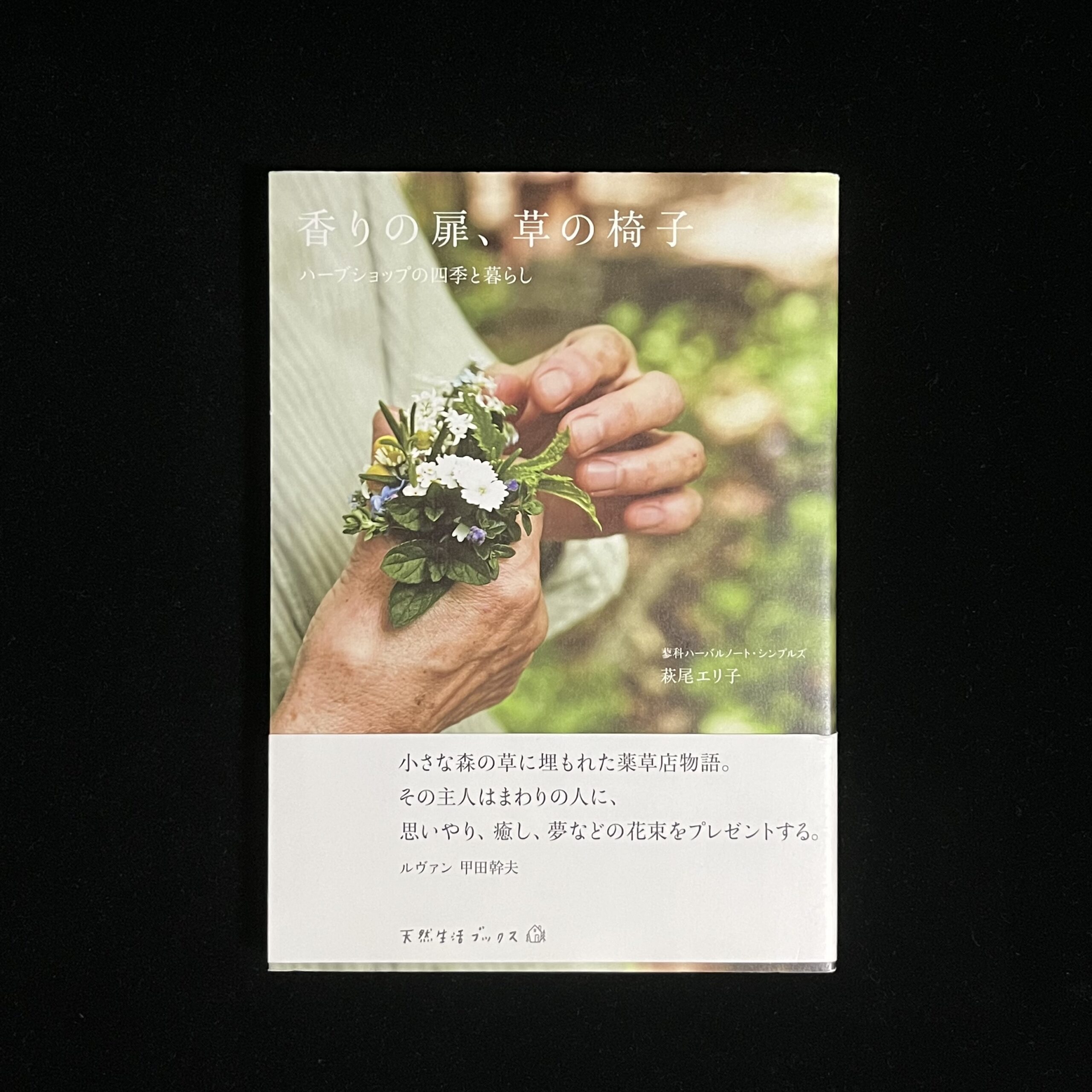 『香りの扉、草の椅子』の本の表紙の写真。白や紫のお花の手にはいるほどの小さな花束を作っている写真が載っています。