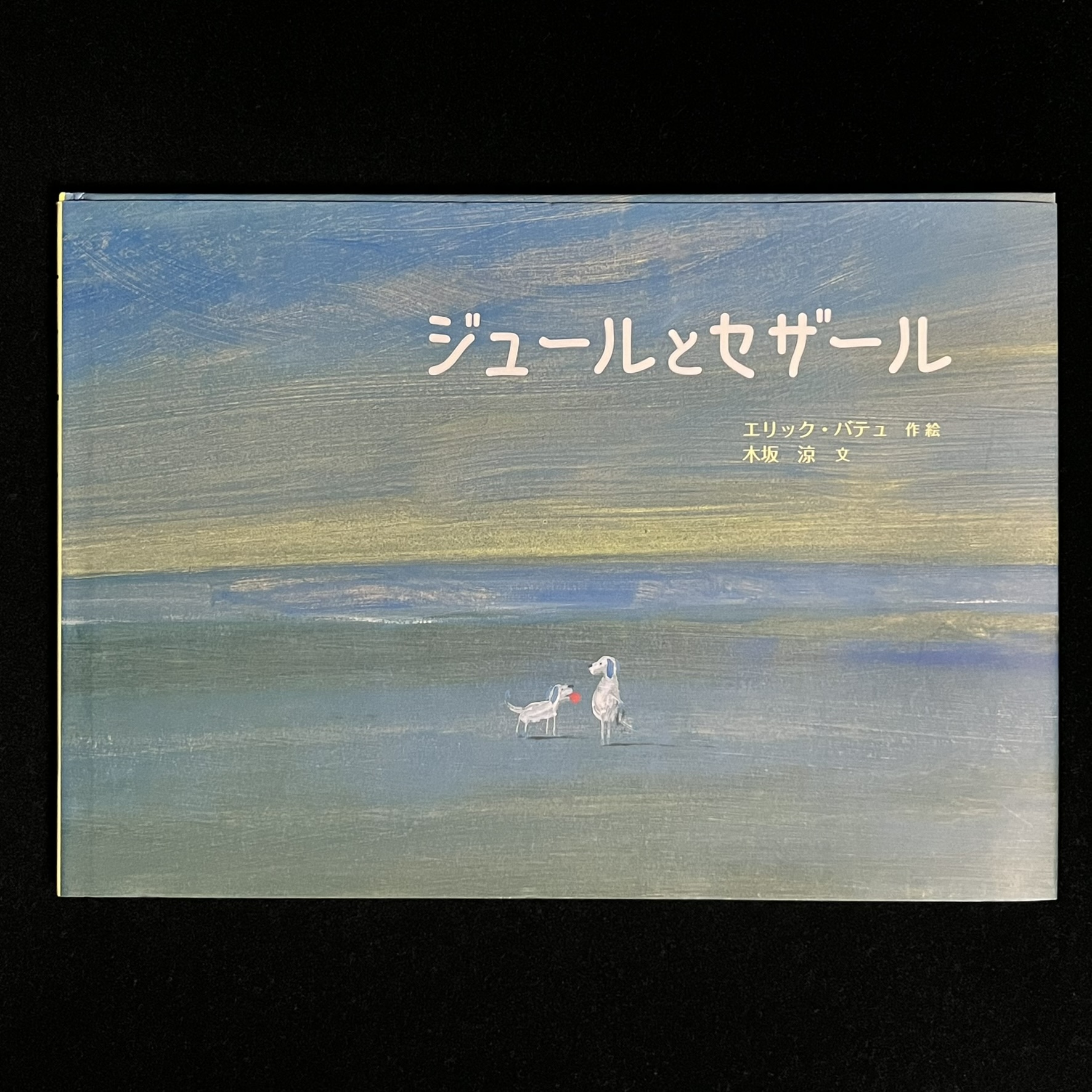 『ジュールとセザール』の絵本の表紙です。 犬のセザールが飼っているジュール。立っているセザールに、ジュールが赤いボールをくわえて持ってきているイラストが描かれています。