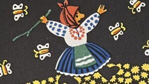 『わらの牛』の絵本のページのイラストです。農夫の奥さんが黄色い花の中を歩いている絵が描かれています。