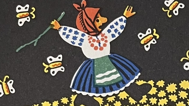 『わらの牛』の絵本のページのイラストです。農夫の奥さんが黄色い花の中を歩いている絵が描かれています。