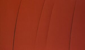 『フォンタナ展』の図録のページの作品の写真です。 赤い布に切れ目がいくつか入っている作品です。